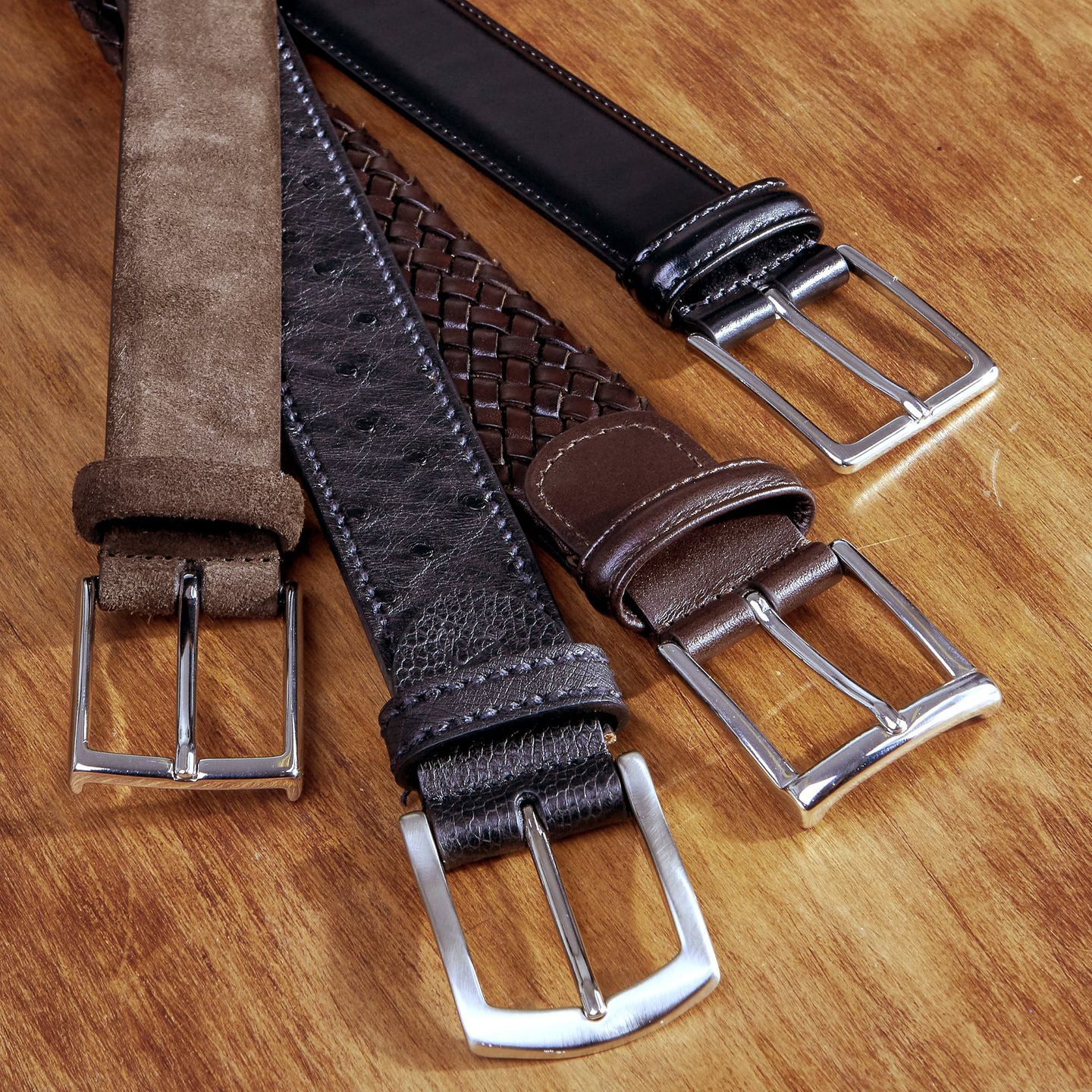 Guide Essential Belts. A picture of three woven leather belts from Andersons: one braided brown belt, one black plain leather belt and one suede belt. The fourth belt is a ostrich belt from Canali.
