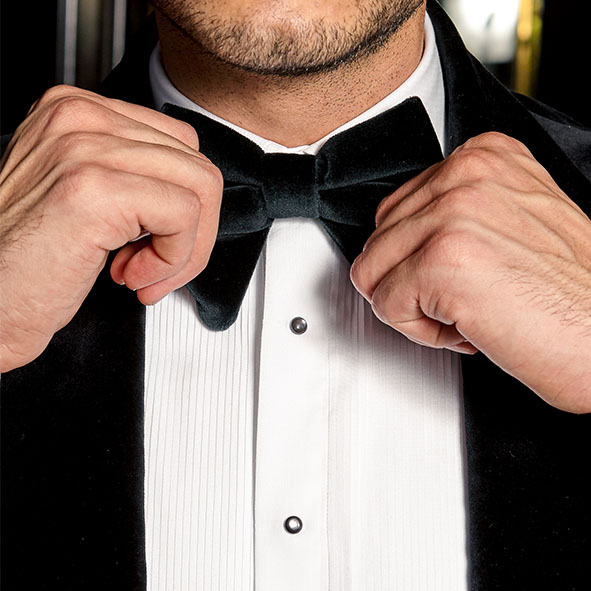 hands fixing a velvet bowtie with tuxedo
