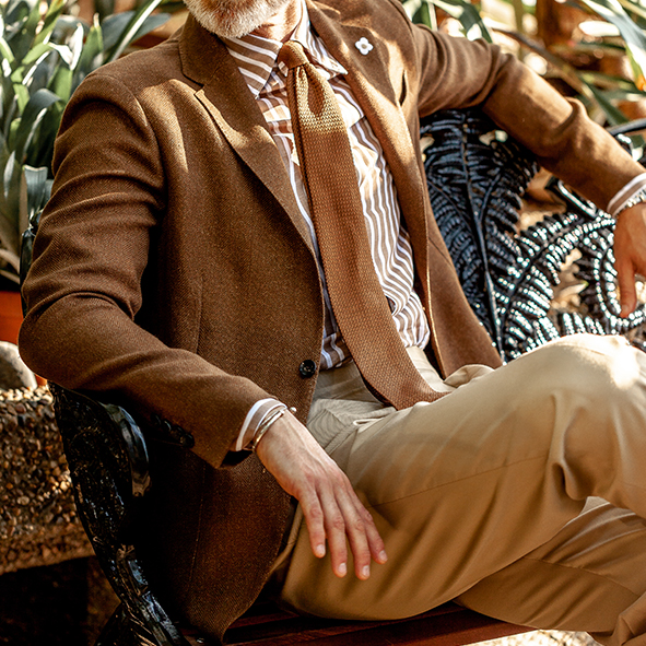 model sitting on a bench with a brown Lardini blazer and brown tie